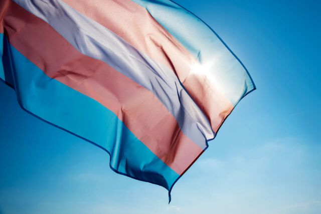 Η τρανς σημαία ανεμίζει με φόντο γαλάζιο ουρανό